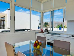 a kitchen with a glass table with chairs and windows at Alojamiento Vacacional con balcón La Vela in Puerto Calero