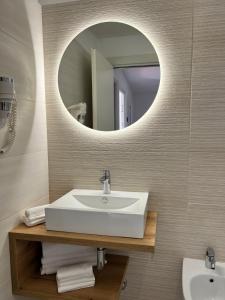 een badkamer met een witte wastafel en een spiegel bij Hotel Sirena - Servizio spiaggia inclusive in Peschici +52 foto's