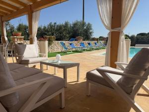 a patio with chairs and a table and a pool at Trullo Blue in Ceglie Messapica