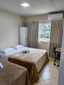 a hotel room with two beds and a window at Pousada Palmeira Imperial in Trombudo Alto
