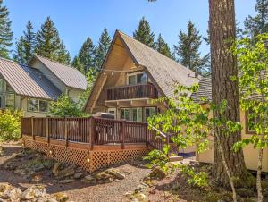 a home with a wooden deck and a tree at Coal Creek Chalet | Creek, AC, Pet Friendly in Packwood