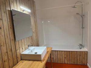 a bathroom with a white sink and a bath tub at L Authentique Prairie in Alès