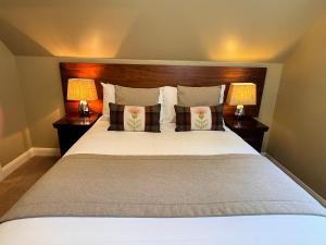 a bedroom with a large bed with two lamps at Allt Nan Ros Cottage in Fort William