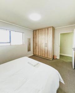 - une chambre avec un grand lit blanc et des placards en bois dans l'établissement Modern One Bedroom Apartment Next to Canal Walk Mall, au Cap
