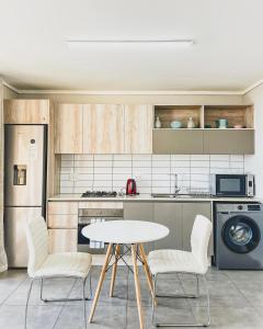 - une cuisine avec une table, 2 chaises et un évier dans l'établissement Modern One Bedroom Apartment Next to Canal Walk Mall, au Cap