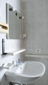 a white bathroom with a sink and a mirror at Hotel Majore in Santa Teresa Gallura