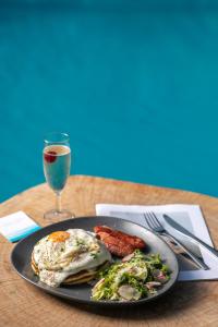 a plate of food with eggs and bacon and a glass of wine at Electra Hotel in Stavros