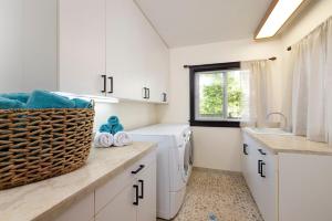 a laundry room with white cabinets and a sink at Hale Holawa Mana-Oceanfront Sunset Beach in Haleiwa +42 photos