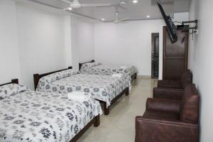 a room with three beds and a chair at Hotel Tania in Caucasia