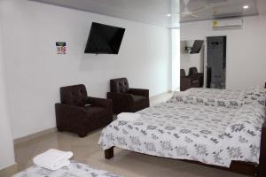 a bedroom with a bed and two chairs at Hotel Tania in Caucasia