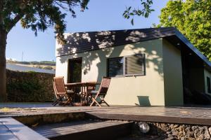 a tiny house with a table and chairs on a deck at Caloura Suite in Caloura