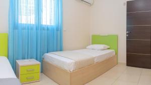 a small bedroom with a bed and blue curtains at Harmony House in Faliraki