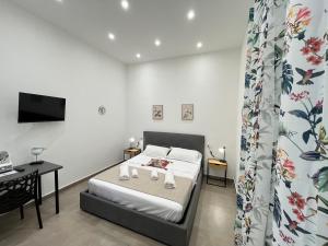 a bedroom with a bed and a desk and a tv at Vesuvio Rainbow FLY in Naples