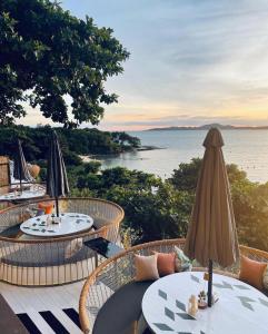 a patio with tables and umbrellas overlooking the water at Stunning Sea View Condo -Next To Beach in Pattaya South