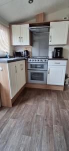 cocina con armarios blancos y horno de acero inoxidable en Blue Water Retreat, en Dawlish Warren