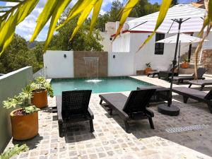 a pool with two chairs and a table and umbrellas at Casona San Cayetano Suites & Lofts & Spa by SCE in Guanajuato