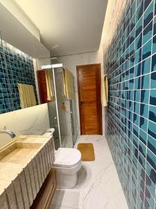 a bathroom with a toilet and a sink and blue tiles at Chalevillebarrinha Presidencial Terrace Suite in Barrinha