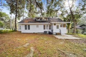 a white house in a yard with trees at Southern Porch Life in Ocala