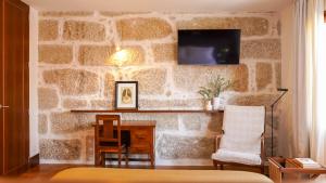 a room with a stone wall with a desk and a tv at Being Porto Hostel in Porto