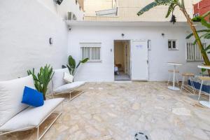 a patio with white furniture and a white wall at Carmen Beach Hostel Cullera in Cullera