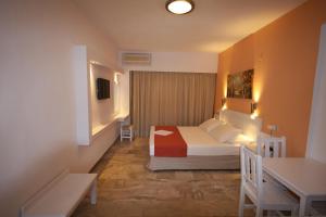 a bedroom with a bed and a table and a desk at Hotel Korali in Troulos