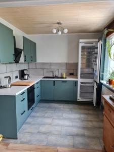 a kitchen with blue cabinets and an open refrigerator at Ferienwohnung in der Ahornstrasse in Gifhorn
