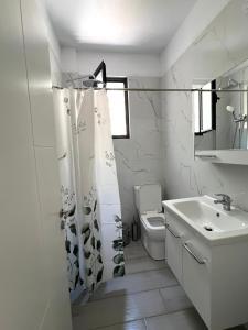 a white bathroom with a toilet and a sink at Duka Apartments Sarande in Sarandë