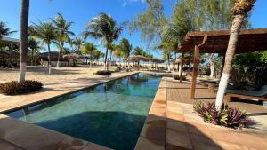 a swimming pool at a resort with palm trees at Recanto da Praia Pousada in São Miguel do Gostoso