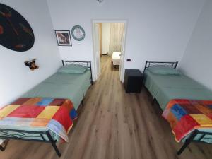 two beds in a room with wooden floors at Regina in Altare