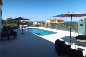 a swimming pool with umbrellas on a patio at Ferienhausanlage Adria Oasis in Višnjan