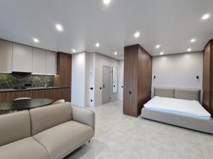 a bedroom with a bed and a couch and a kitchen at ApartReserve Avtorskiy Aparthotel in Ivano-Frankivsk