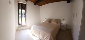 a white bedroom with a bed and a window at Casa ATARAXIA in Boiro