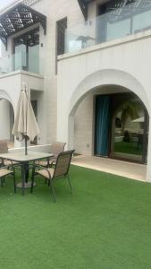 un patio con mesa, sillas y césped verde en Hawana salalah, en Salalah