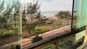 a window with a view of a road and the ocean at Sossego e Conforto à Beira Mar in Capão da Canoa