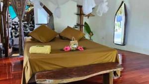 a bedroom with a bed with flowers on it at TAHITI ITI - Saltwater Family Huts in Teahupoo