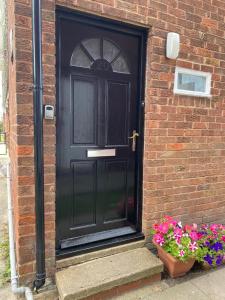 a black door on a brick building with flowers at Spacious Town Centre Apartment in Barnsley