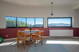 a dining room with a table and chairs and windows at Swiss Agricultural School Caucasus in Sarkinetʼi +9 photos