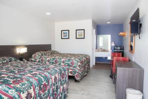 a hotel room with two beds and a television at Nogalitos Motel in San Antonio