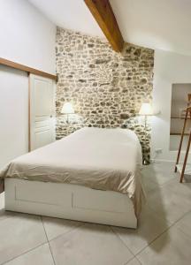 Un dormitorio con una cama blanca y una pared de piedra. en Le Bastion, 15 guests, 5 suites, 5 baths, AC, en Pouzols-Minervois