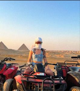 a woman riding a quad bike in front of the pyramids at ayla pyramids inn in Nazlet el-Sîsi