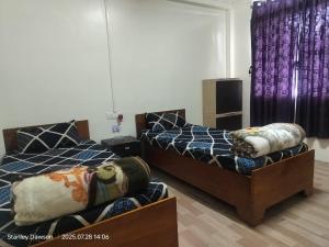 twee bedden in een kamer met paarse gordijnen bij Ado Homestay in Shillong +2 foto's