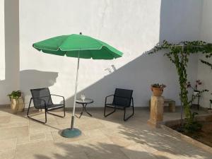 two chairs and a green umbrella on a patio at Vico Grazie in Campi Salentina