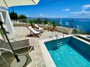 a swimming pool with an umbrella and chairs next to it at Sofias Retreat Nissaki in Katávolos