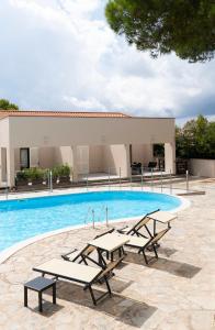 a swimming pool with two benches in front of a building at L'Alzaia in Chioma