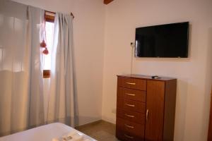a bedroom with a dresser and a television on a wall at Hotel Cafayate in Cafayate