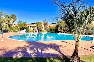 a large swimming pool with a palm tree next to it at Votre Villa Soleil et Chaleureuse in Marrakesh