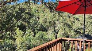 a red umbrella sitting on top of a wooden deck at Yosemite Mountain Retreat in Oakhurst