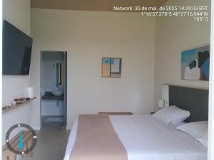 a bedroom with a large white bed and a bathroom at KAA Flat in Belém