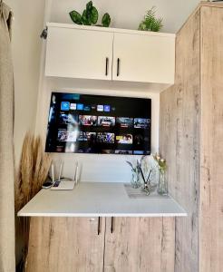 Un escritorio con un televisor de pantalla plana encima de un armario. en SoftPod Loft in Prime Location Fourways, en Sandton