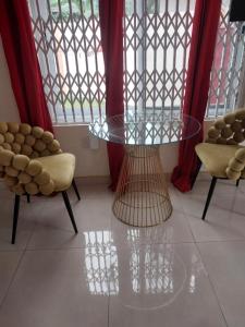 a glass table and two chairs in a room with windows at PorshStudioAppartment Dzorwulu in Accra